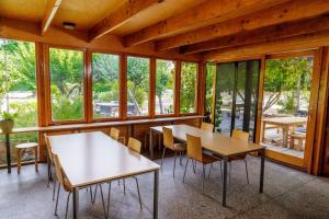 two tables and chairs in a room with windows at YHA Grampians Eco, Halls Gap in Halls Gap