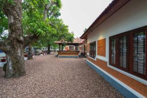 a courtyard of a building with a tree at The Backwater Heritage- Comp Breakfast with River View & Lawn by StayVista in Alleppey
