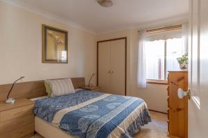 ein Schlafzimmer mit einem Bett mit einer blauen Decke und einem Fenster in der Unterkunft Fishermans Delight Waterfront in Sussex inlet
