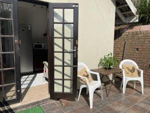a patio with two chairs and a table and a door at Comfrey cottage in Kloof