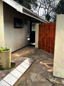 a house with a wooden fence next to a driveway at Comfrey cottage in Kloof