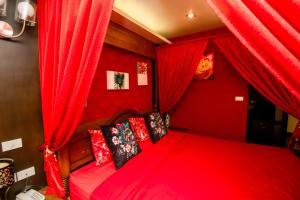 ein rotes Schlafzimmer mit einem Bett mit roten Vorhängen in der Unterkunft Sabai Sabai@Sukhumvit Hotel in Bangkok