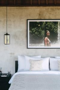 um quarto com uma cama branca e uma fotografia na parede em DABA - Designer Villas in Perenenan - Beach 600M em Canggu