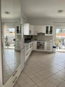 a large kitchen with white cabinets and a tile floor at Dina Apartment in Skala