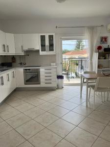 una cucina con armadi bianchi, un tavolo e una sala da pranzo di Dina Apartment a Skala di Cefalonia