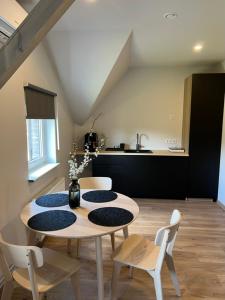 a dining room with a table and chairs and a kitchen at Mazā Kaija in Bērzciems