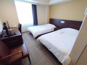 Habitación de hotel con 2 camas y escritorio en New Matto Terminal Hotel, en Hakusan