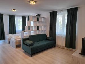 uma sala de estar com um sofá verde e uma cama em Orion Panzió em Hajdúszoboszló