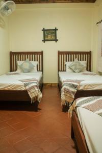 two beds in a room with a tiled floor at laolulodge in Luang Prabang