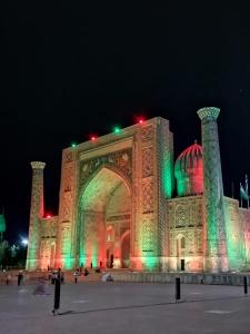 un edificio iluminado por la noche con luces verdes en Royal lux Guest House, en Samarkand