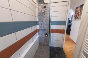 Cette chambre dispose d'une douche et d'un mur en carrelage. dans l'établissement KASA Cocon - Entièrement équipé avec Balcon, à Saint-Étienne