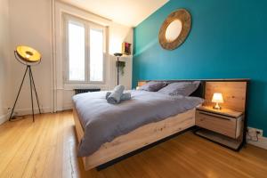 1 dormitorio con 1 cama grande y pared azul en KASA Cocon - Entièrement équipé avec Balcon, en Saint-Étienne