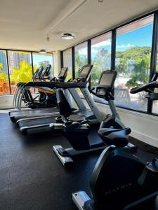 Luana Waikiki Park Views في هونولولو: صالة ألعاب رياضية مع العديد من أجهزةالجري في غرفة بها نوافذ