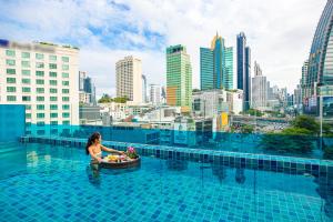 a woman in a pool with a bowl of fruit at Hotel Clover Asoke - SHA Extra Plus in Bangkok