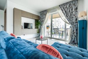 a living room with a blue couch and a large window at Lovely chic studio, on a beautiful promenade in Braşov