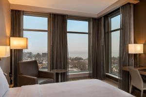 a hotel room with a bed and a desk and windows at AC Hotel by Marriott Madison Downtown in Madison