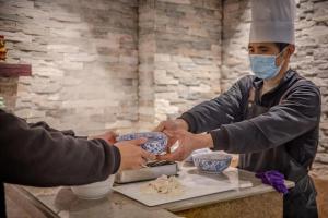 a man in a mask serving food from a table at Yiwu Manting Hotel International Trade City义乌漫庭酒店 in Yiwu