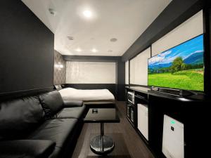 ein Wohnzimmer mit einem Sofa und einem Flachbild-TV in der Unterkunft HOTEL 31 in Funabashi