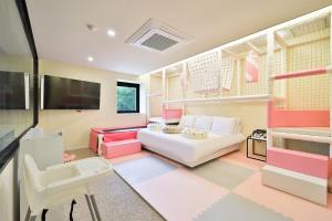 uma sala de estar com um sofá branco e mobiliário rosa em Doan Kids Hotel Yangsan em Yangsan
