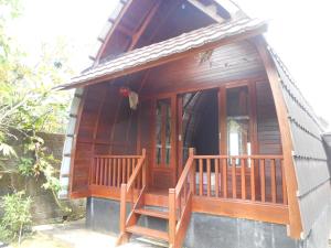 a small house with a wooden porch and stairs at Candra Homestay Besakih in Besakih