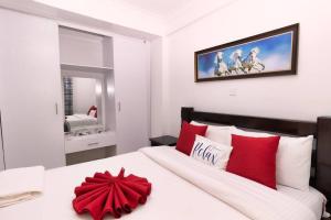 een slaapkamer met een groot wit bed met rode kussens bij Levi's Place 1044 California Plaza Nanyuki in Nanyuki