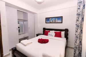 a bedroom with a large white bed with red pillows at Levi's Place 1044 California Plaza Nanyuki in Nanyuki