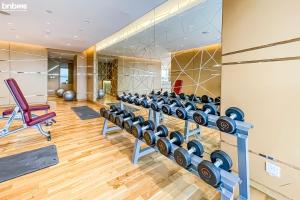 a gym with rows of dumbbells and a red chair at bnbmehomes - Damac Hills Studio w City View - 2504 in Dubai