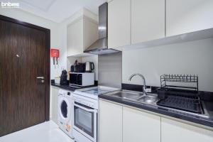 a kitchen with a sink and a washing machine at bnbmehomes - Damac Hills Studio w City View - 2504 in Dubai