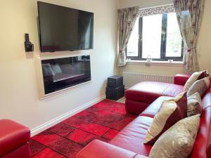 a living room with two red couches and a flat screen tv at The Apartment in Nairn