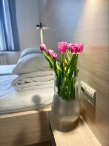 a vase of pink tulips on a table in a bedroom at Villa Kmeller in Lviv