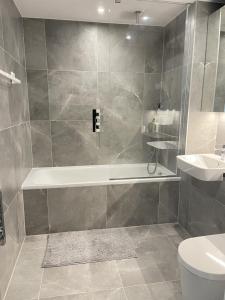 a bathroom with a tub and a toilet and a sink at Luxurious Room Near Train Station in London