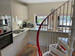 a kitchen with white cabinets and a spiral staircase at The Apartment in Nairn