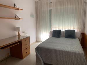 a bedroom with a bed with a desk and a window at ATICO PLANAS céntrico frente mar in Salou