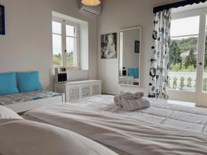 a white bedroom with a large bed and a window at Villa Ancora Spetses in Spetses