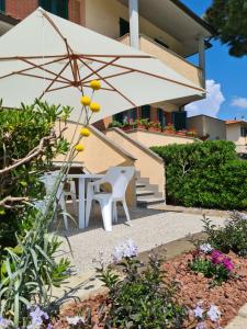 a white table and chairs with an umbrella at Villaggio Mietta in Castiglioncello