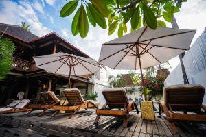 um grupo de cadeiras e guarda-sóis num deque em Villa Luna Sunset Beach em Gili Trawangan