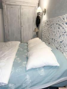 een bed met een wit hoofdeinde en kussens erop bij maison cosy et spa zen en Flandres et côte d'opale in Hondschoote