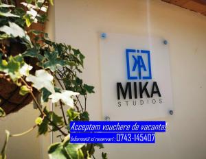 a sign for a miya studios on a wall with a plant at MIKA Studios in Eforie Nord