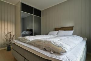a large white bed in a bedroom with a mirror at Perfekt base for det meste! in Leknes