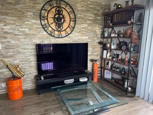 ein Wohnzimmer mit einem Kamin, einer Uhr und einem TV in der Unterkunft Les jardins de jade Disney in Ferrières-en-Brie