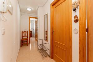 a hallway with a wooden door and some chairs at San Sebastián 22 in Torrevieja +18 photos