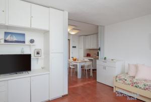a living room with a couch and a tv and a kitchen at Iole's House, finestra sul mare in Olbia