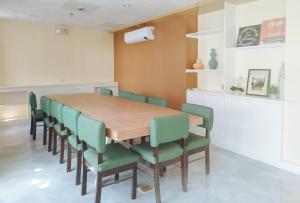 PaviaにあるRedDoorz @ Benelio Suites Pavia Iloiloのダイニングルーム(木製テーブル、緑の椅子付)