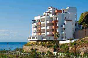 a building on a hill next to the ocean at Apartamento de 2 dormitorios en Torrox Costa in Torrox Costa