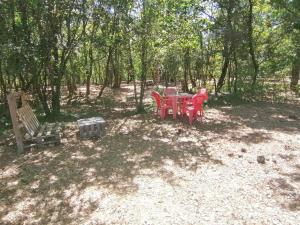 Emplacement tente camping car في Saint-Aubin-de-Nabirat: طاولة نزهة وكراسي في ظل الأشجار