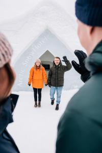 Un gruppo di persone che si trovano di fronte a un igloo di neve di Arctic SnowHotel & Glass Igloos a Sinettä