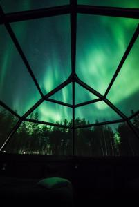 einen Blick auf die Aurora aus einem Glas-Iglu in der Unterkunft Arctic SnowHotel & Glass Igloos in Sinettä