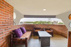uma parede de tijolos com sofás e uma mesa com almofadas roxas em FabHotel Brown Inn em Pune