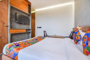 1 dormitorio con 1 cama y TV de pantalla plana en FabHotel Brown Inn en Pune