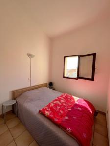 Un dormitorio con una cama con una manta roja. en Appartement 4 personnes piscine 300 plage 4PB287 en Le Barcarès